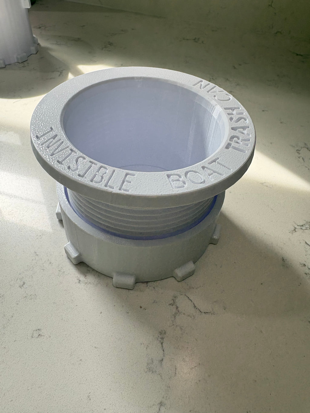 A white plastic boat trash can with a circular lid, featuring embossed text reading 'BOAT TRASH CAN' and 'INVISIBLE'.